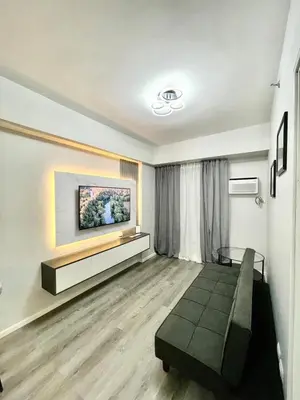 a living room with a couch and a tv on a wall at Nyli Minimalist Suite in Manila