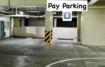 an empty parking lot with a pay parking sign in a parking garage at Nyli Minimalist Suite in Manila