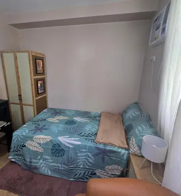 a small bedroom with a bed with a blue comforter at Metrotowne PHINMA Las Pinas in Manila