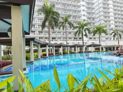a large swimming pool in front of a large building at PinkdoorZ Moa Staycation at Shell Residences in Manila