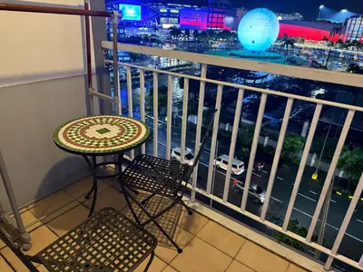 a table and chair on a balcony with a view of a city at PinkdoorZ Moa Staycation at Shell Residences in Manila