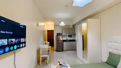 a living room with a television and a kitchen at Bella Suite Netflix Pool Great View in Manila