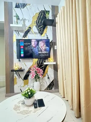 a room with a table and a tv on a wall at Suite Elegante - Sea Residences Mall of Asia Pasay in Manila
