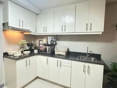 a kitchen with white cabinets and a sink at Suite Elegante - Sea Residences Mall of Asia Pasay in Manila
