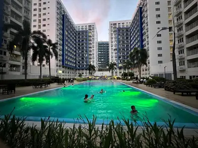 a group of people in a swimming pool with buildings at Suite Elegante - Sea Residences Mall of Asia Pasay in Manila