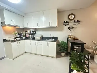 a kitchen with white cabinets and a clock on the wall at Suite Elegante - Sea Residences Mall of Asia Pasay in Manila