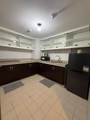 a kitchen with brown cabinets and a black refrigerator at California Gardens square in Manila