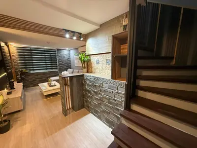 a living room with a stone wall and a staircase at California Gardens square in Manila