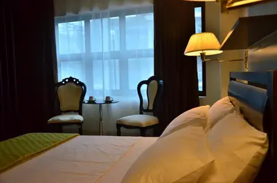 a bedroom with a bed and two chairs and a window at Oriental Zen Suites in Manila