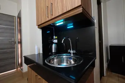 a kitchen with a stainless steel sink on a black counter at Oriental Zen Suites in Manila