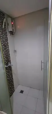 a white bathroom with a shower with a glass door at Solemare Parksuites in Manila