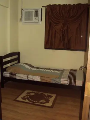 a small bed in a room with a window at Tropical Hawaiian 2BR Condo Unit in Metro Manila with Laundry Area - Sleeps 4 in Manila