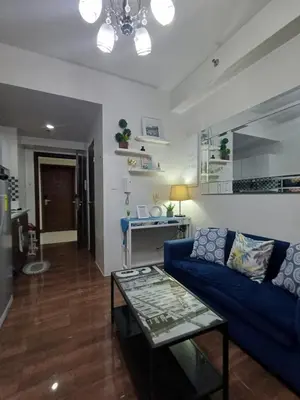 a living room with a blue couch and a table at Florian's suite in Air Resideneces Makati in Manila