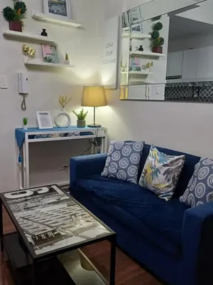 a living room with a blue couch and a table at Florian's suite in Air Resideneces Makati in Manila