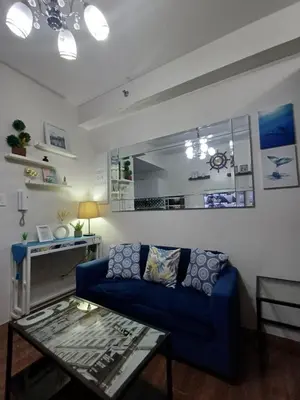 a living room with a blue couch and a table at Florian's suite in Air Resideneces Makati in Manila