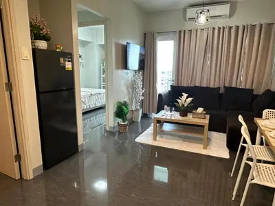 a living room with a black refrigerator and a table at Suite Haven - Sea Residences MOA PASAY in Manila