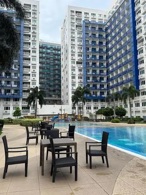 a row of tables and chairs next to a swimming pool at Suite Haven - Sea Residences MOA PASAY in Manila