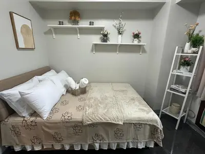 a bedroom with a bed with white pillows and shelves at Suite Haven - Sea Residences MOA PASAY in Manila