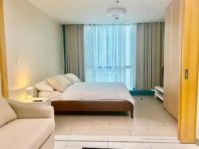 a bedroom with a bed and a couch at One Uptown Residence BGC 1BR sofabed in Manila