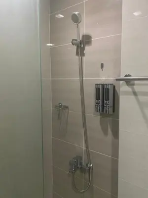 a shower with a glass door in a bathroom at One Uptown Residence BGC 1BR sofabed in Manila
