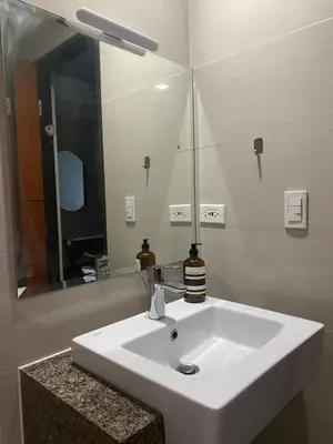 a bathroom with a white sink and a mirror at One Uptown Residence BGC 1BR sofabed in Manila