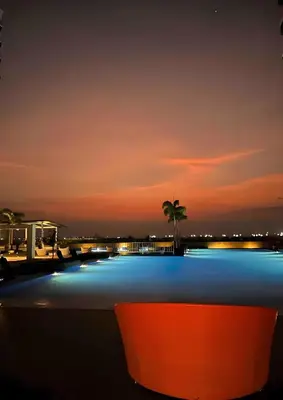 a pool at night with a palm tree in the background at Modern 1BR with Magnificant Garden View, Near Airports, Okada, Solaire with Free Parking in Manila