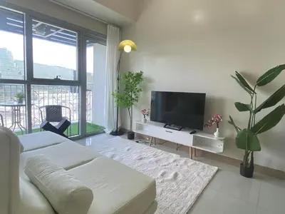 a living room with a white couch and a flat screen tv at Modern 1BR with Magnificant Garden View, Near Airports, Okada, Solaire with Free Parking in Manila