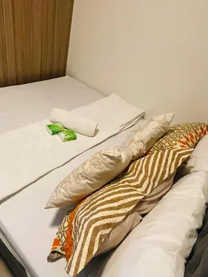 two unmade beds with pillows on them in a room at Shore Residences Moa Pasay in Manila