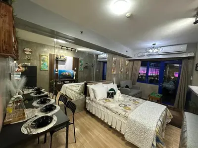 a room with a bed and a table with chairs at Balai Bacasionan - Sea Residences MOA Pasay in Manila