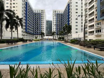 a large swimming pool in the middle of some buildings at Balai Bacasionan - Sea Residences MOA Pasay in Manila