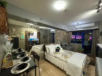 a bedroom with a bed and a table with chairs at Balai Bacasionan - Sea Residences MOA Pasay in Manila