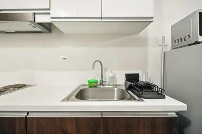 a kitchen with a sink and a refrigerator at Makati 1BR with Skyline View at Air Residences in Manila