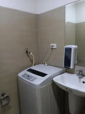 a bathroom with a washing machine and a sink at Shore Staycation with two beds in Manila