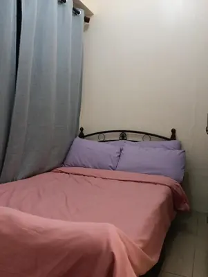 a bedroom with a bed with pink sheets and blue pillows at Shore Staycation with two beds in Manila