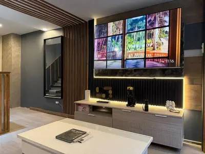 a living room with a tv on a wall at 2 bedroom loft type with 2 baths Near Rockwell in Manila