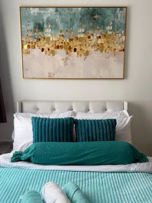 a bed with green pillows and a painting above it at Infinity Suites Makati in Manila