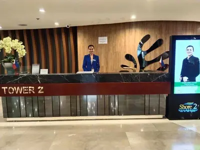 two people standing at a counter in a lobby at 1 BR- with Balcony -Shore 2 Tw2 - Pasay MOA in Manila