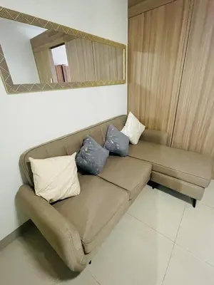 a brown couch in a living room with a mirror at Shore 2 Residences Moa Pasay in Manila