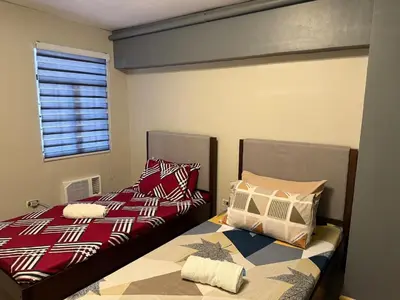 two beds sitting next to each other in a bedroom at 2 bedroom loft type near Rockwell in Manila