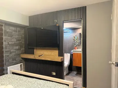 a bedroom with a flat screen tv and a toilet at 2 bedroom loft type near Rockwell in Manila