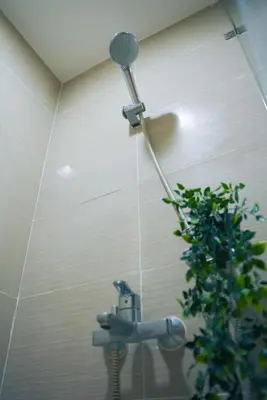 a shower head in a bathroom with a plant at Upscale Stylish Suite Near BGC and View of Venice Grand Canal Mall in Manila