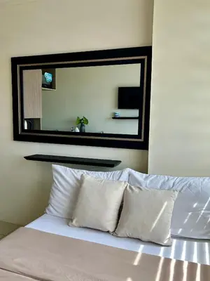a large mirror above a bed with white pillows at NIJECRIFIL Condotel in Manila