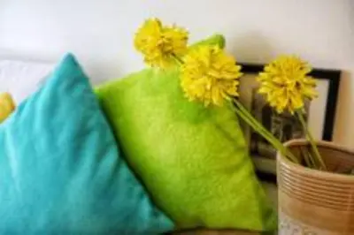 a vase with yellow flowers sitting next to two pillows at 5 mins SM Aura Cozy Studio Type in Manila