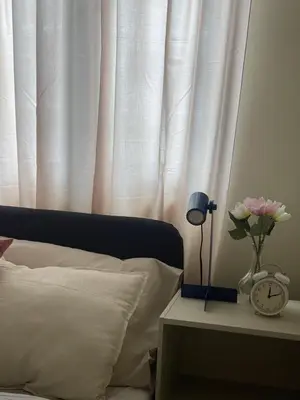 a bed with a white curtain and a table with a clock at cozy 1 bedroom retreat Walk to Moa in Manila