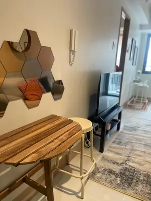 a living room with a bench and a television at cozy 1 bedroom retreat Walk to Moa in Manila