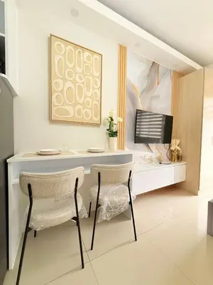 a desk with two chairs and a television in a room at Shell Residences Mall of asia Rs in Manila