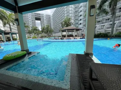 a large swimming pool with people in a building at Shell Residences Mall of asia Rs in Manila