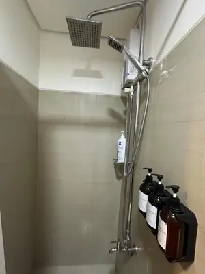 a bathroom with a shower with four bottles of soap at Seaside Manila Bay Sunset View at SM Mall of Asia in Manila