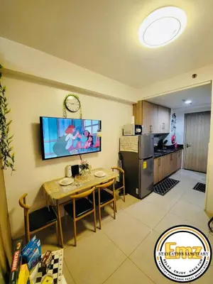 a kitchen with a table and a television on the wall at EMZ Shore Staycation 38 in Manila