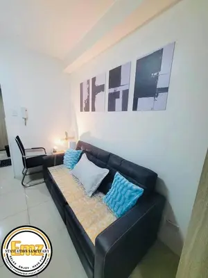 a black couch with blue pillows in a living room at EMZ Shore Staycation 38 in Manila